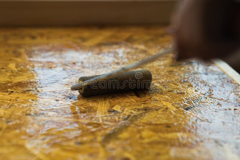 Roller paint brush lacquered osb wooden board. DIY, carpenting and construction concept royalty free stock photos
